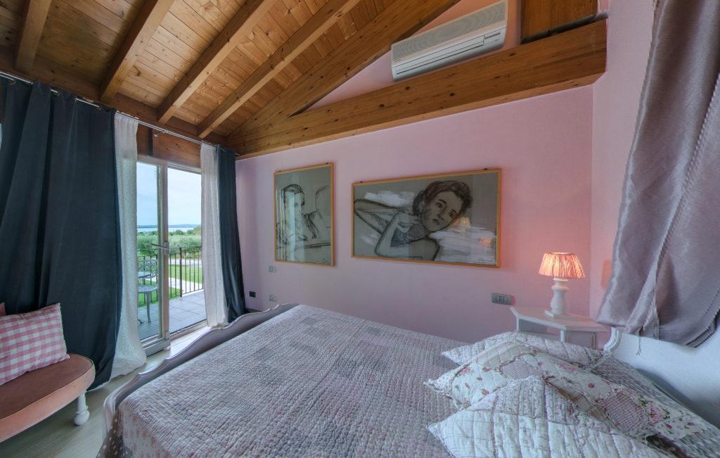 Camera Deluxe con pareti rosa e balcone vista lago