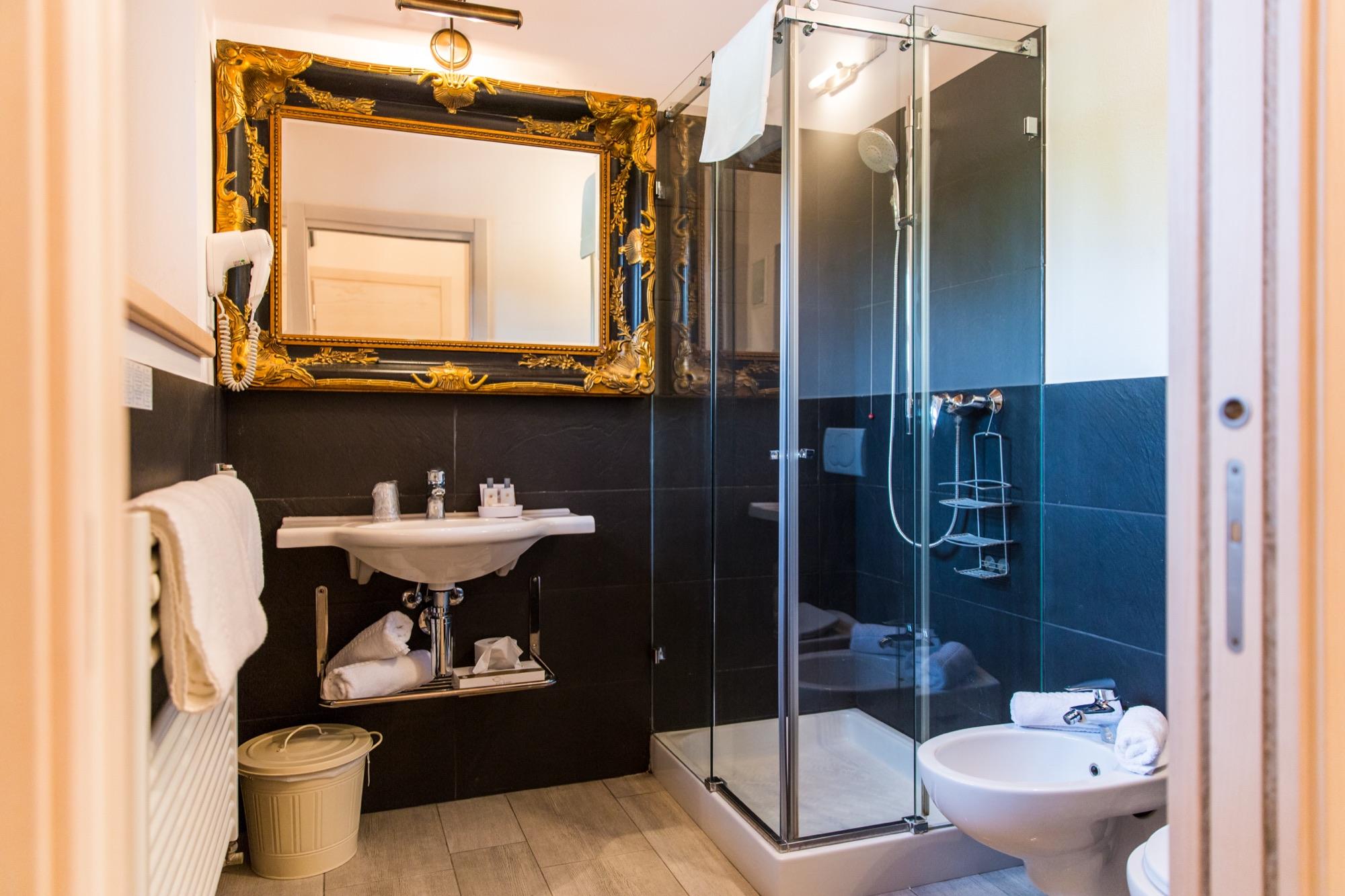 Bagno con specchio dorato e doccia in vetro
